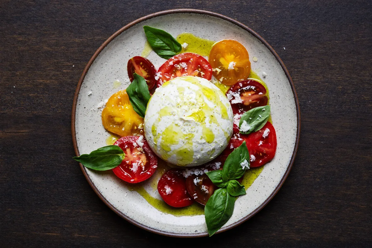 Burrata mit reifen Tomaten und Basilikumöl, von oben fotografiert